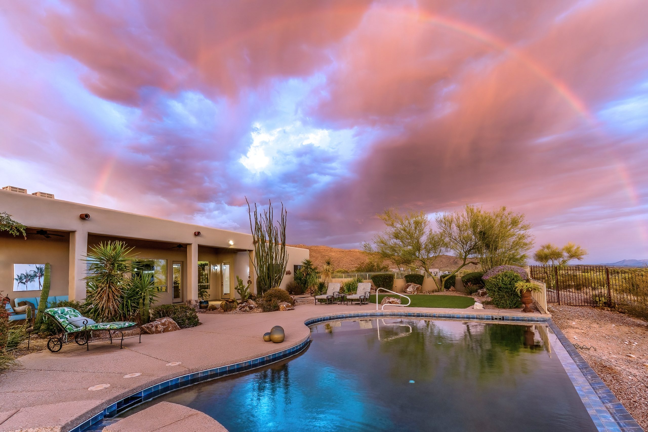 Monsoon storm with rainbow over pool